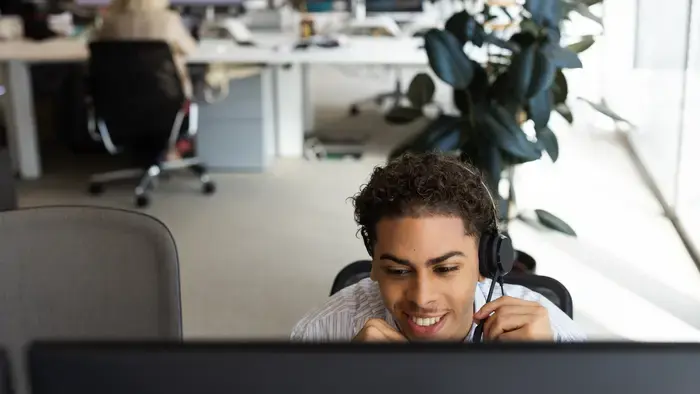 Smiling person wearing headset at computer.