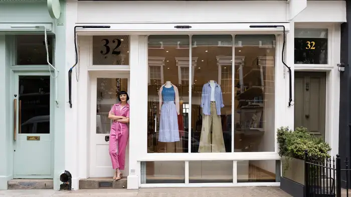 A woman stands outside a clothing boutique.