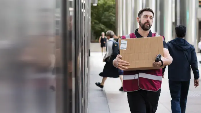 A delivery person walks on-site with a box in hand.