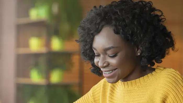 Woman using a touchscreen tablet, smiling with coffee and notebook.