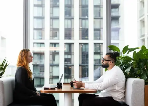 Two coworkers have a meeting at a table.