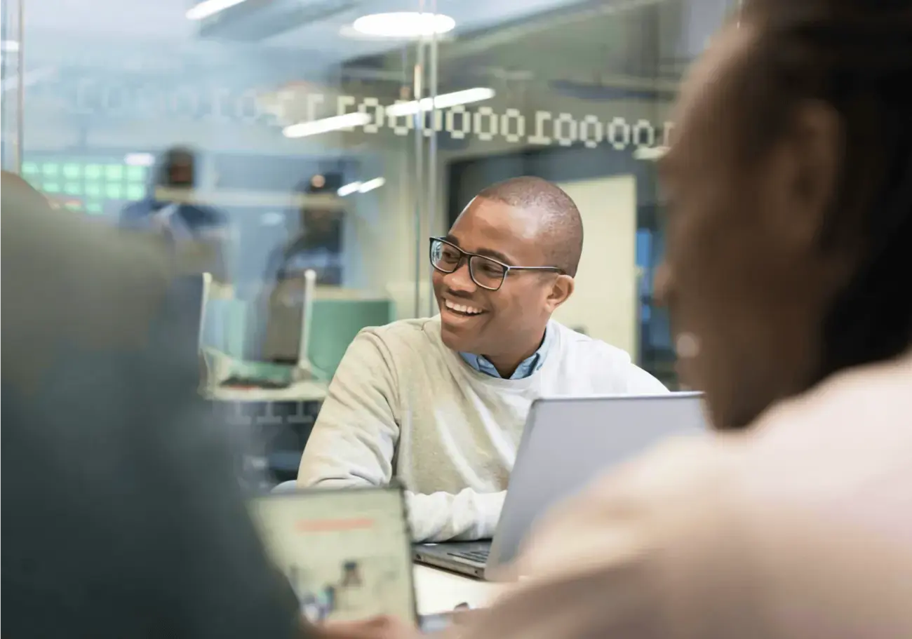A man smiling at his coworker next to him.