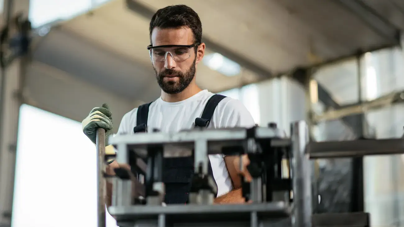 A focused worker in safety glasses operates machinery.