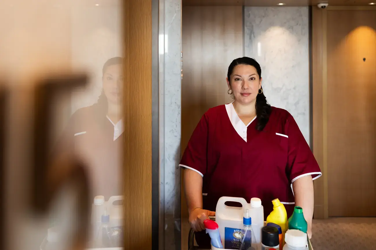 Hotel housekeeper standing by a cleaning cart.