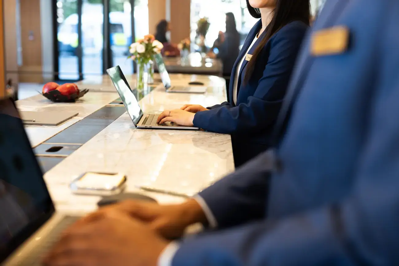 Recepcionistas de hotel em laptops.