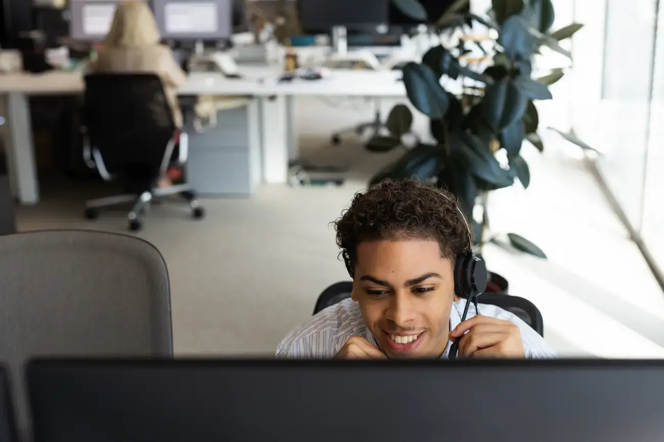 Smiling person wearing headset at computer.