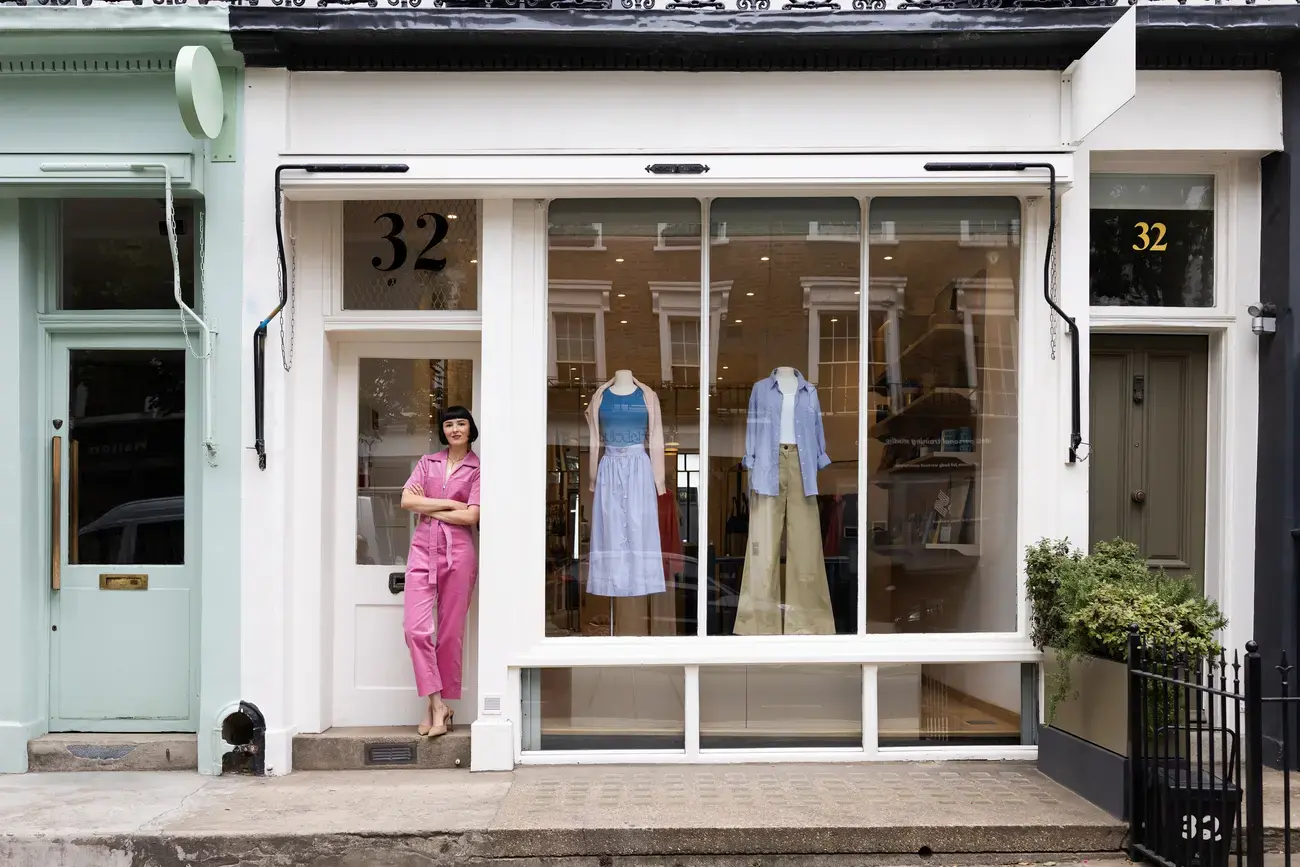 A woman stands outside a clothing boutique.