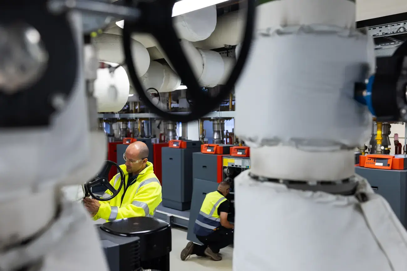 Two maintenance workers inspect industrial machinery.